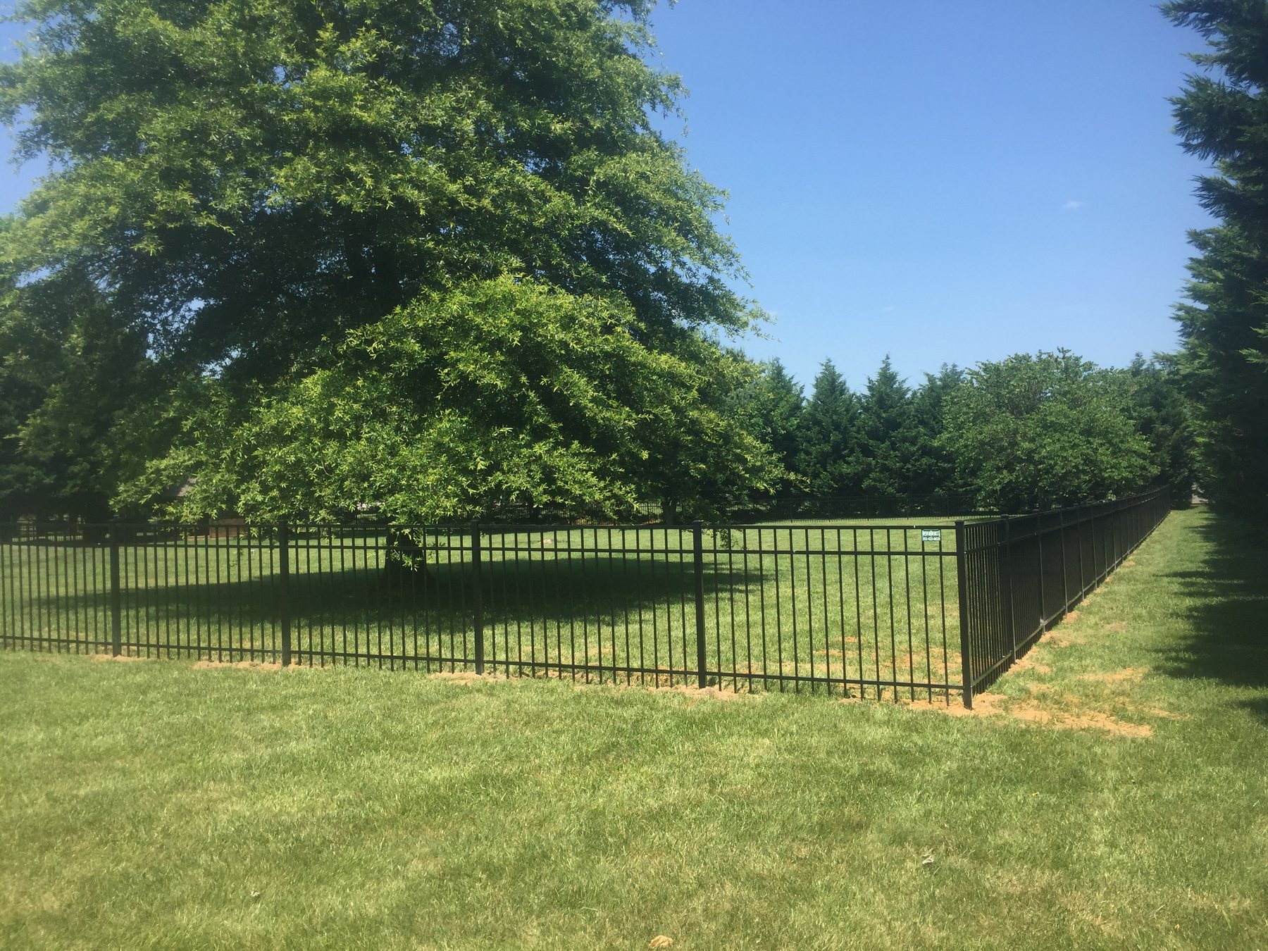 Black 3-rail flat top aluminum fence along a green lawn