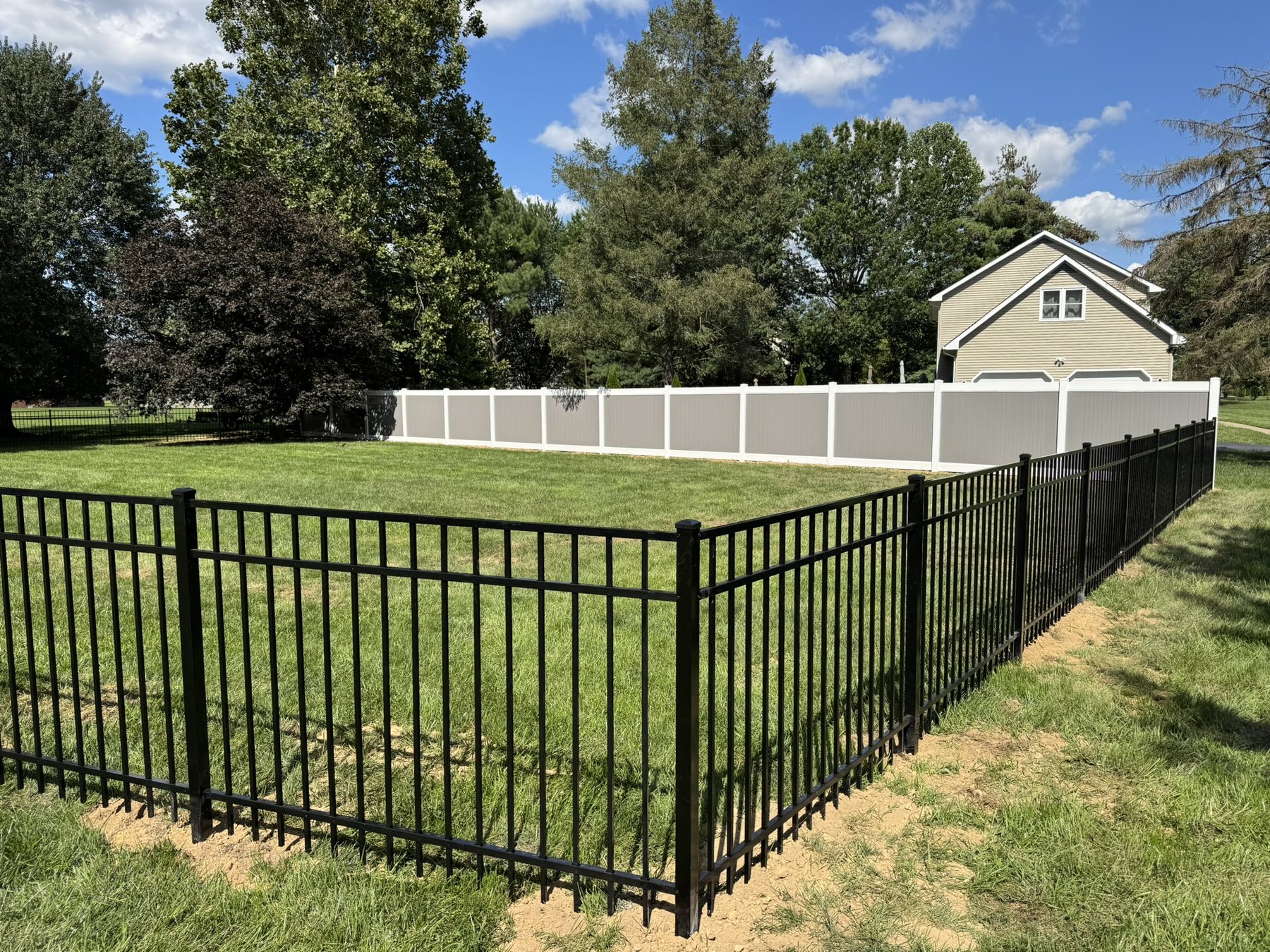 Black 3-rail aluminum fence turning a property corner