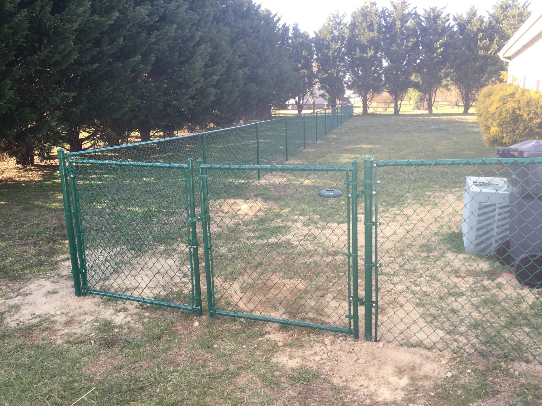 Green vinyl-coated chain link fence with a gate