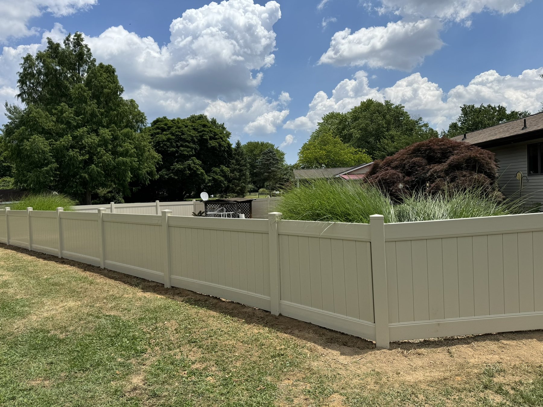 Tan vinyl privacy fence enclosing a residential backyard