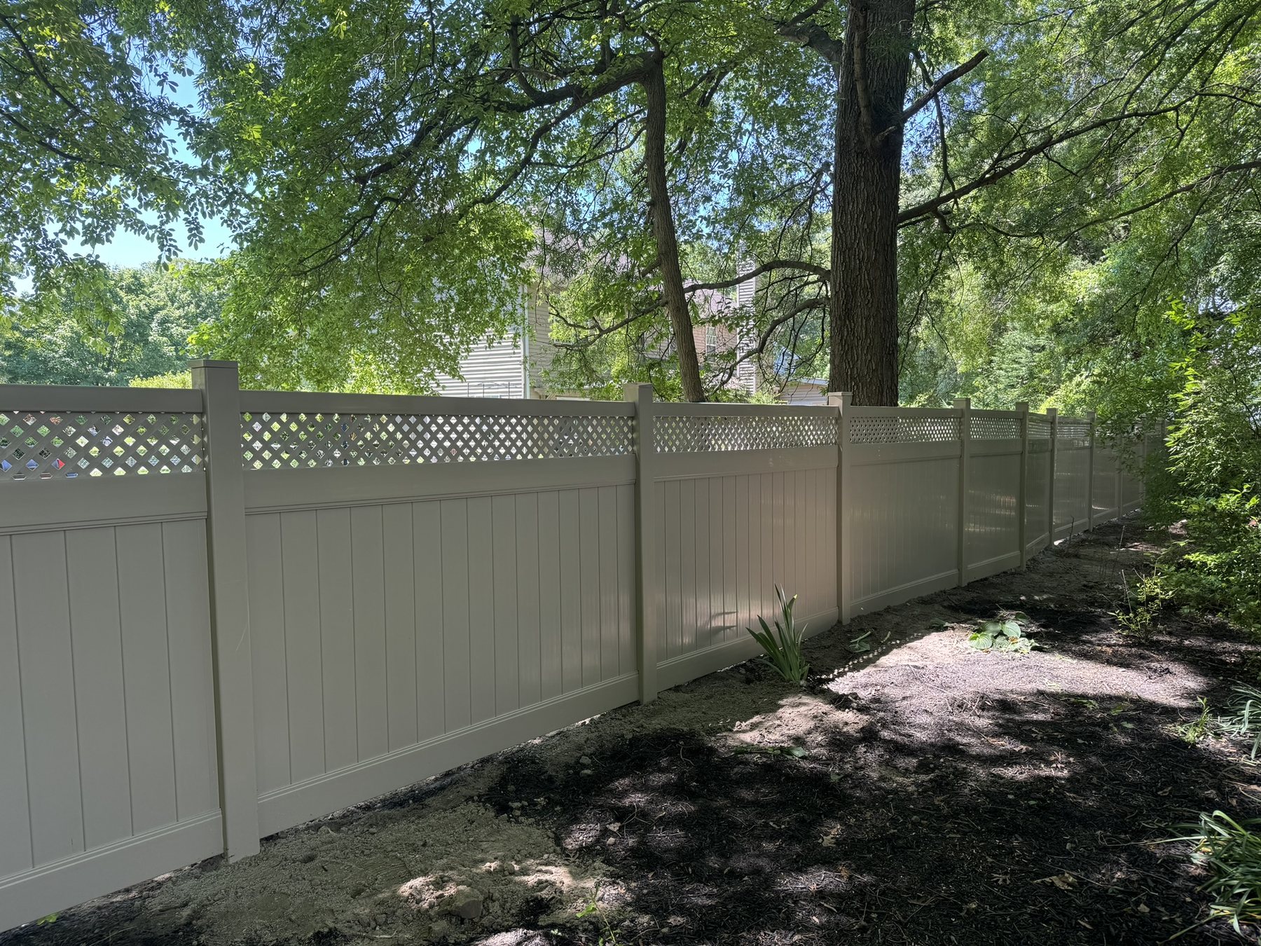 Tan vinyl privacy fence with a lattice top accent