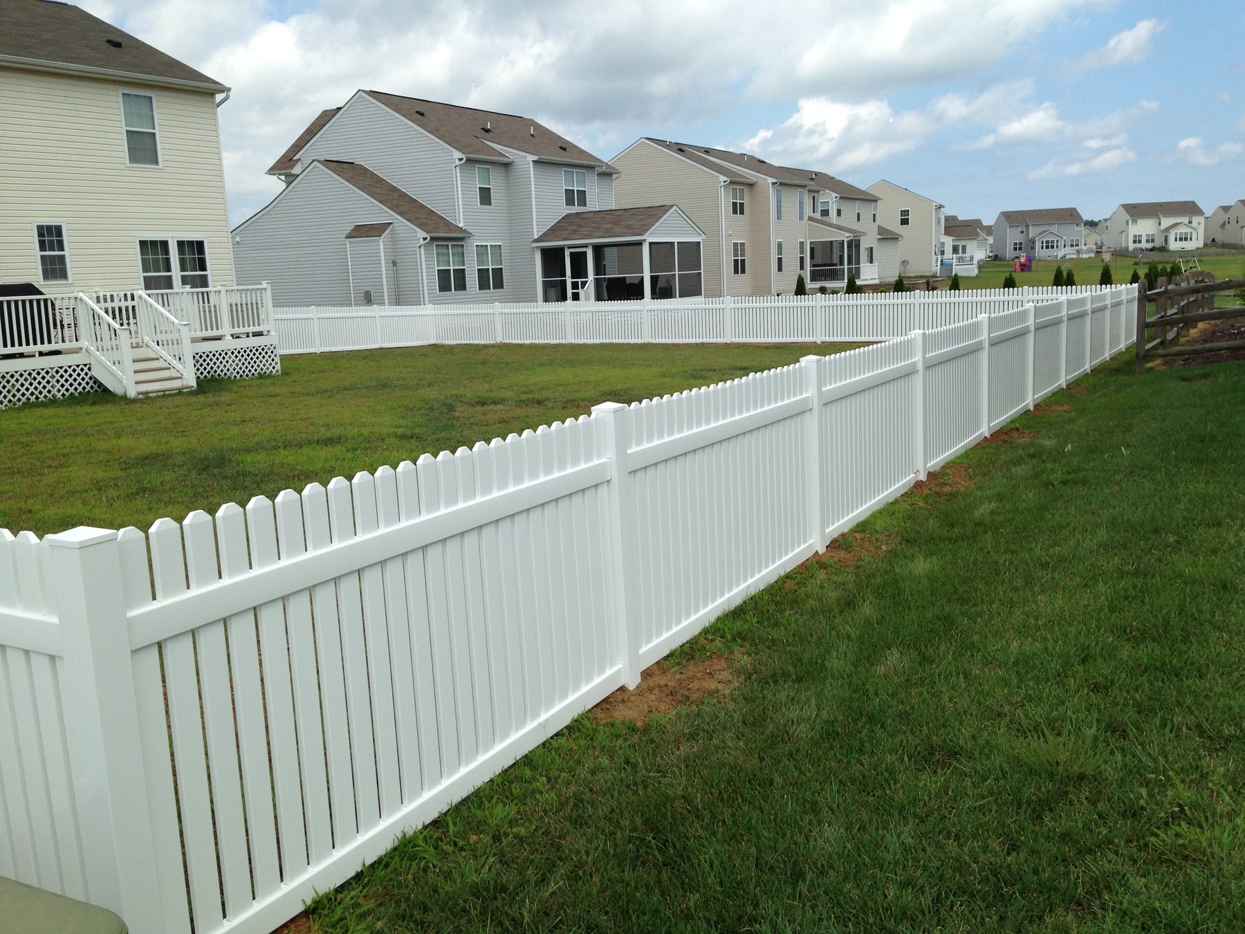 White vinyl picket fence across a front yard