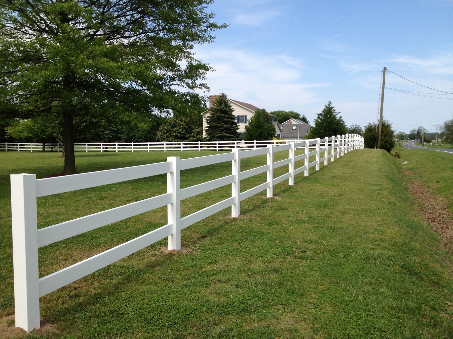 White vinyl ranch rail fence along an open property