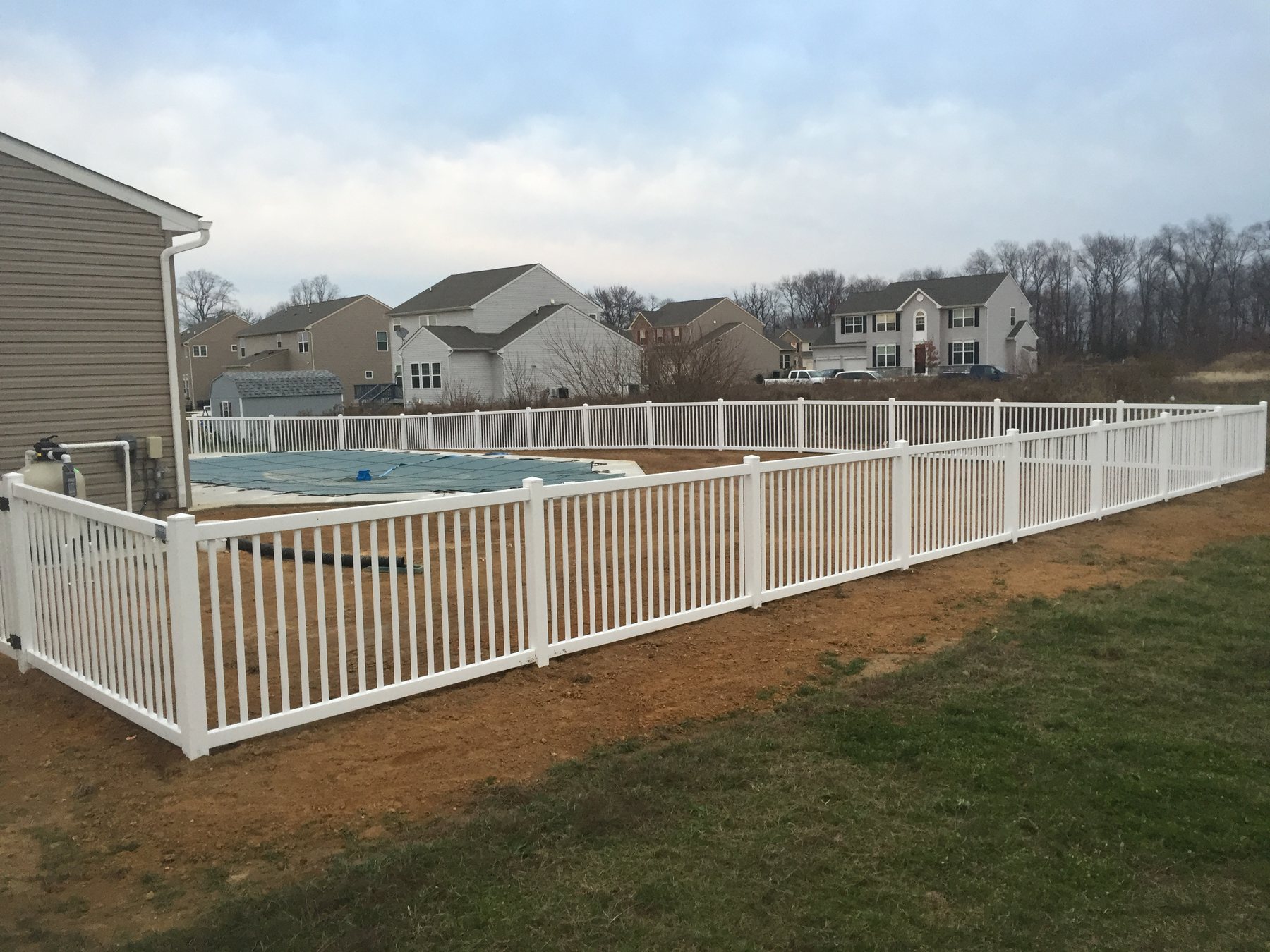 White vinyl pool-code picket fence surrounding a backyard pool