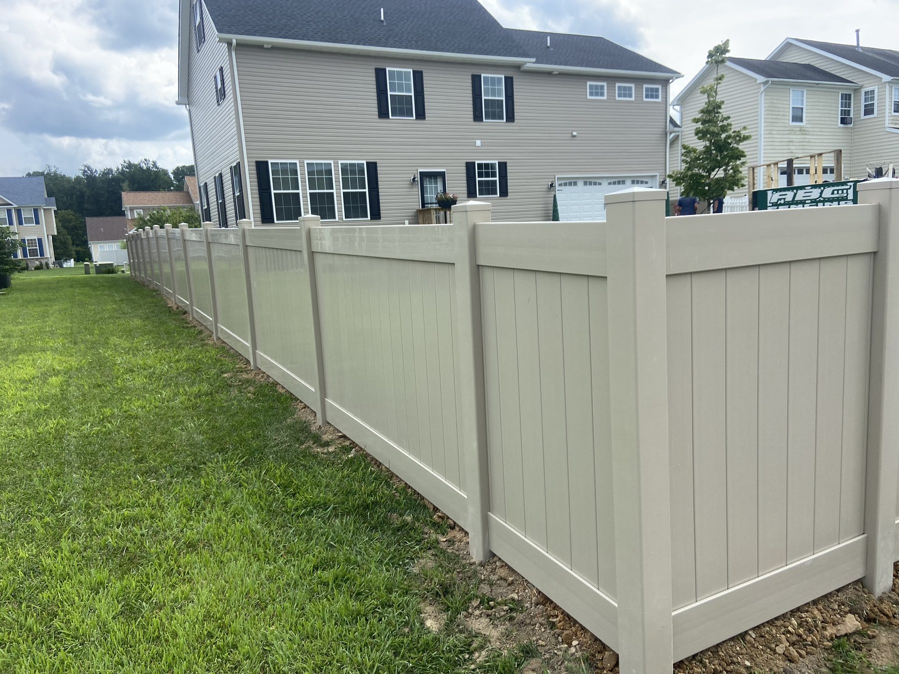 Tan vinyl privacy fence running down the side yard of a home